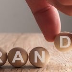 Hand putting on brand word written in wooden ball