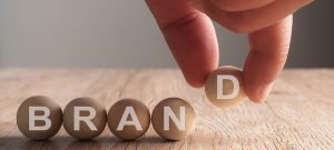 Hand putting on brand word written in wooden ball